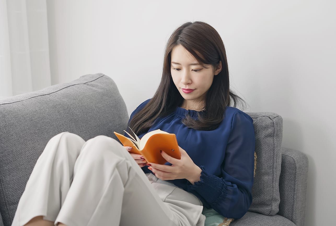 休日に自宅のソファで読書を楽しみリラックスして過ごす様子