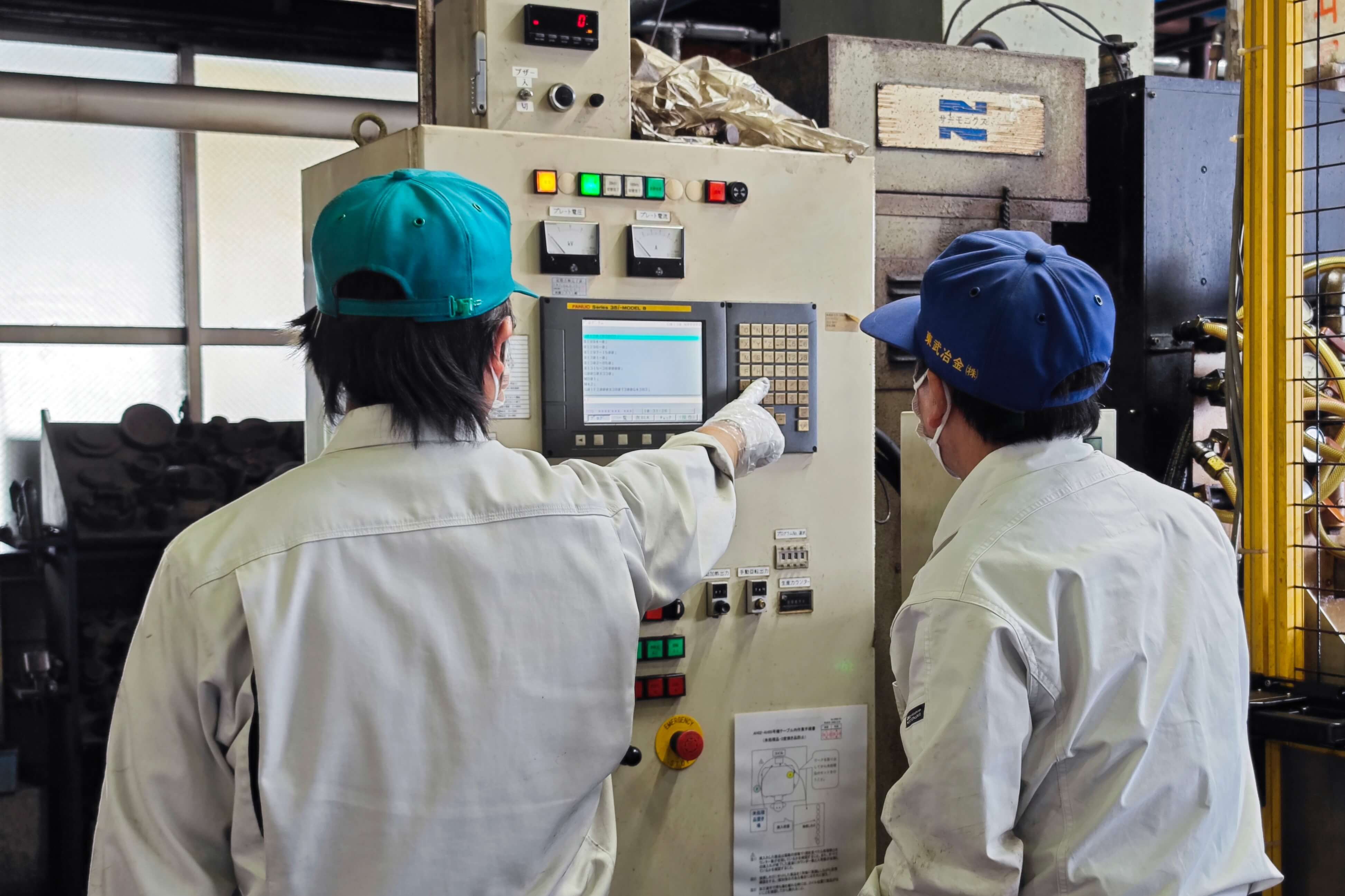 工場の制御盤を操作し、機械の稼働状況を確認する東武冶金のスタッフ