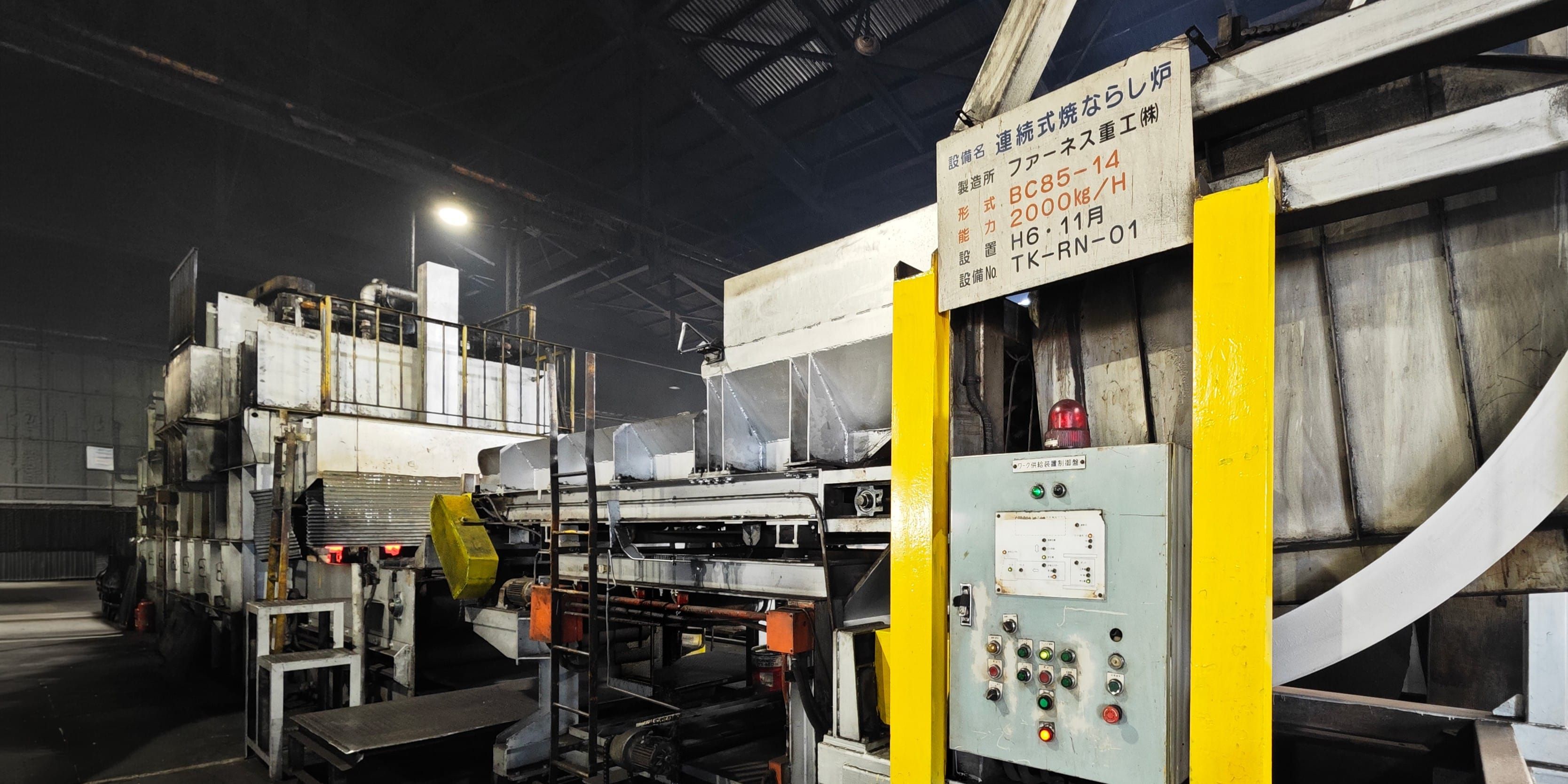 東武冶金の工場内に設置された、連続式焼ならし炉の設備外観と制御用操作パネル。